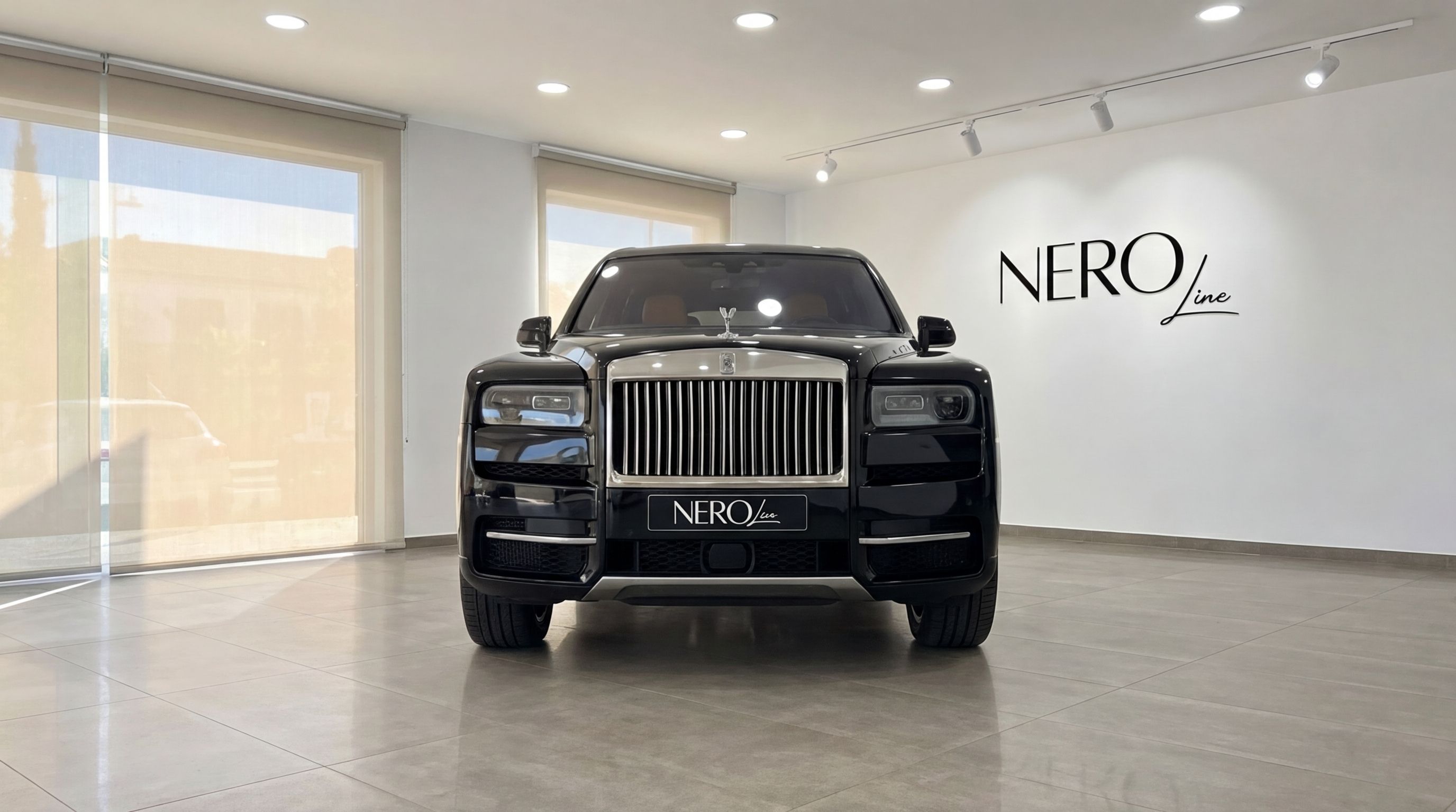 The jet black Rolls-Royce Cullinan 2024 is prominently displayed from a front view in a bright showroom in Ibiza.