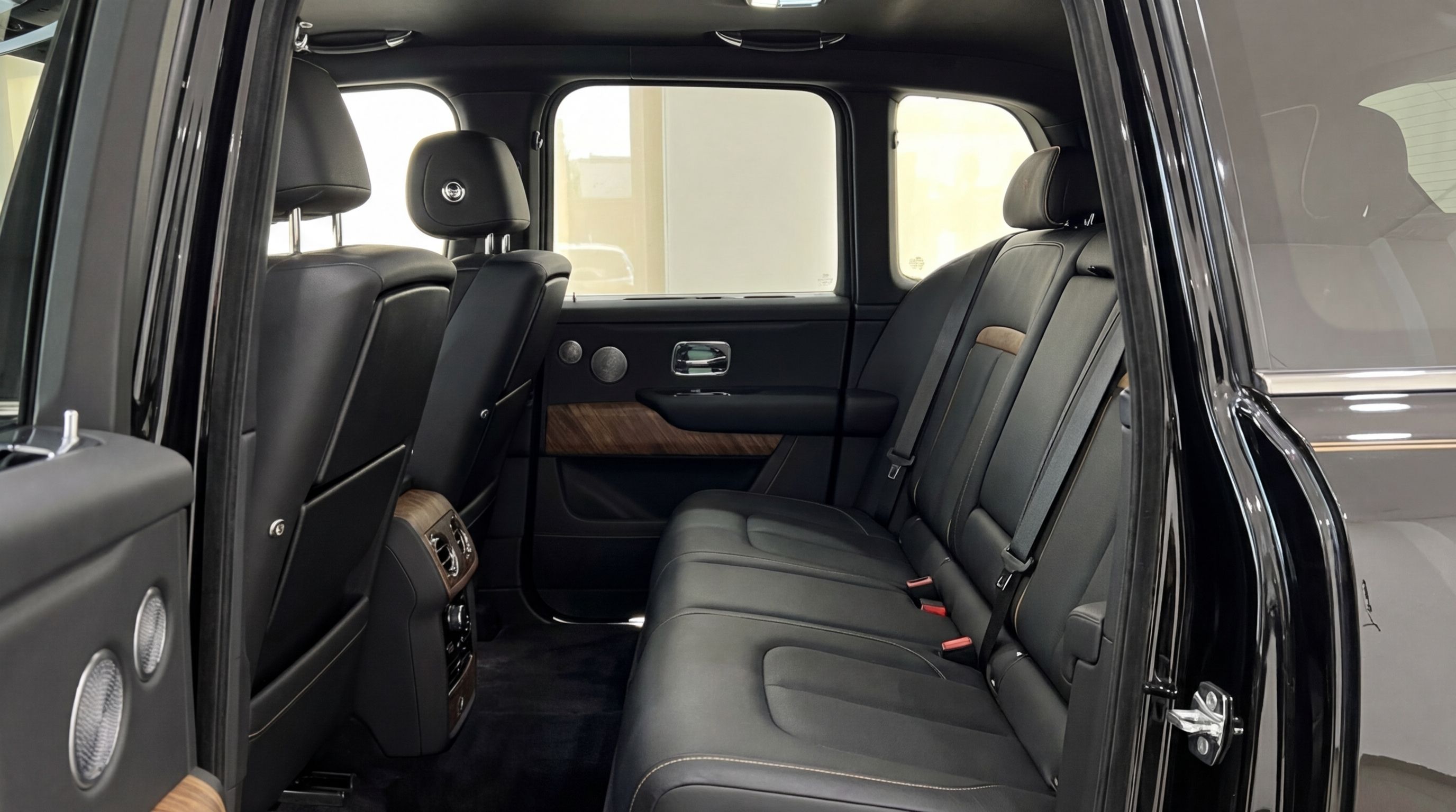 The luxurious rear interior of the Rolls-Royce Cullinan in Ibiza, featuring black leather seats and elegant wood trim.