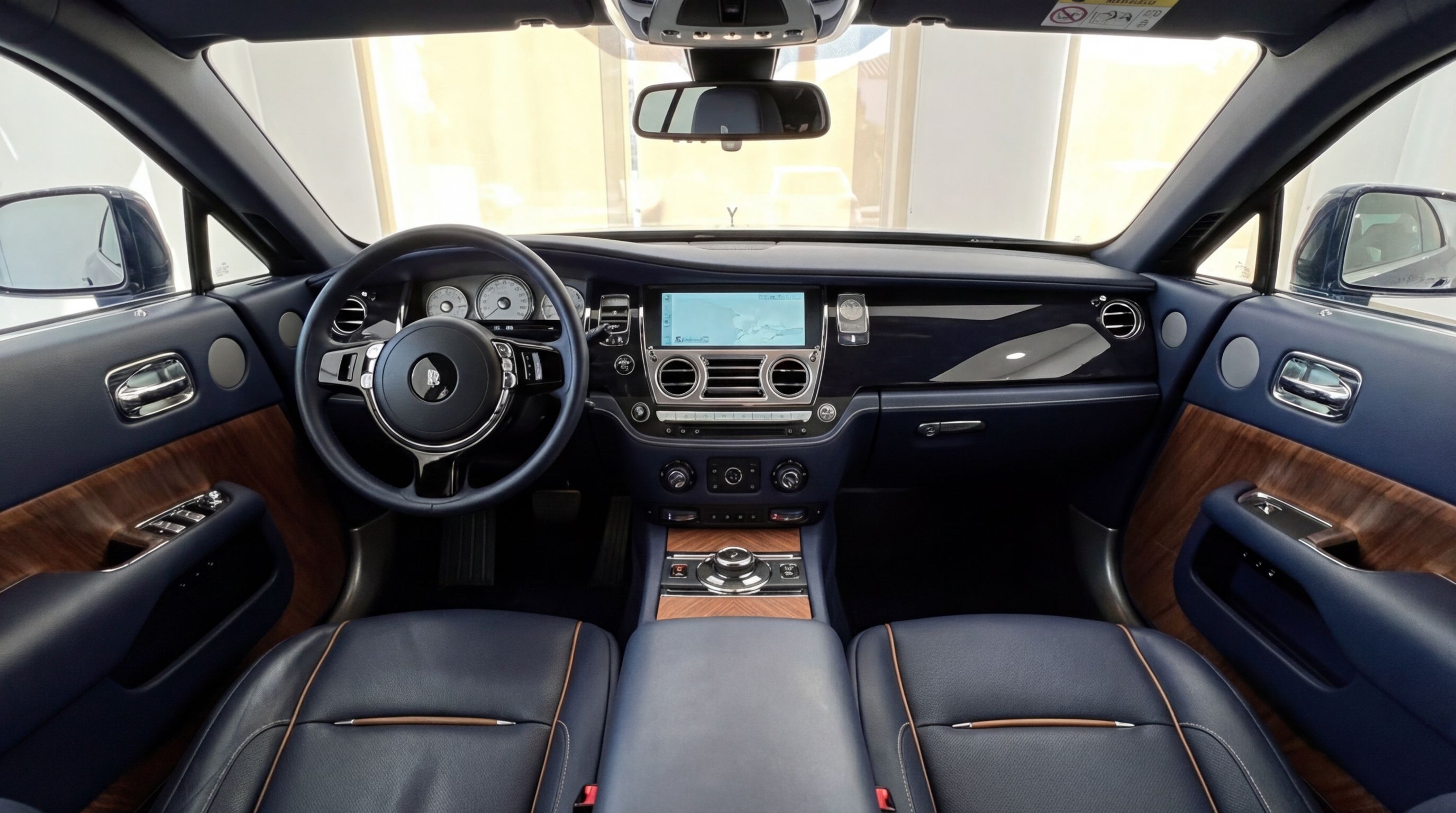 Rolls-Royce Dawn's luxurious cockpit in midnight blue with wood trim, featuring the steering wheel, dashboard, and infotainment screen in Barcelona.