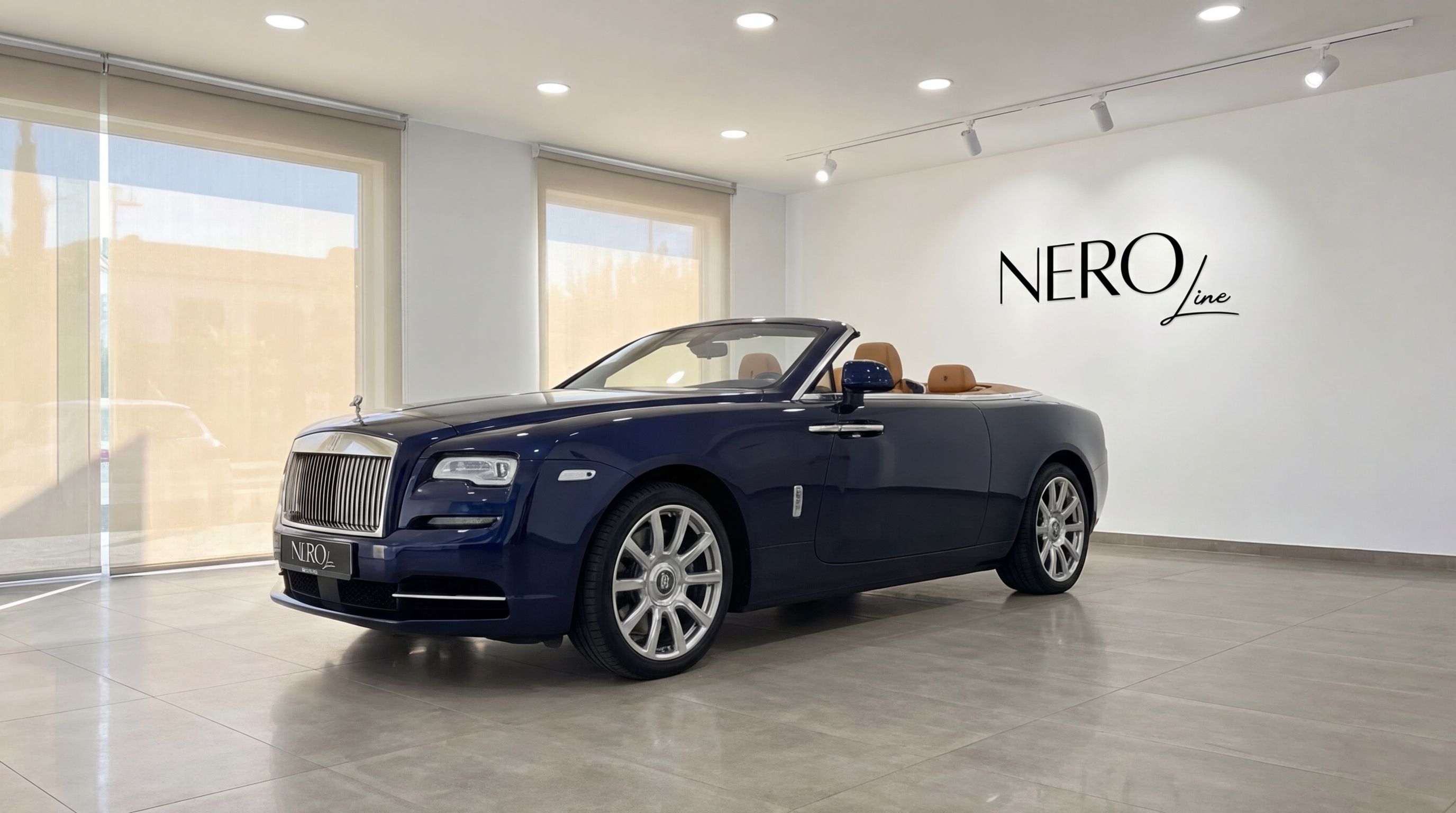 The midnight blue Rolls-Royce Dawn convertible with its top down and tan interior is showcased in a Barcelona showroom.