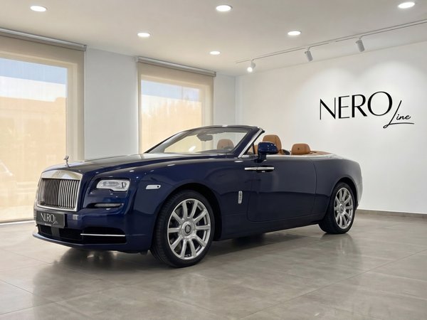 Rolls-Royce Dawn — Midnight Blue Convertible The midnight blue Rolls-Royce Dawn convertible with its top down and tan interior is showcased in a Barcelona showroom.