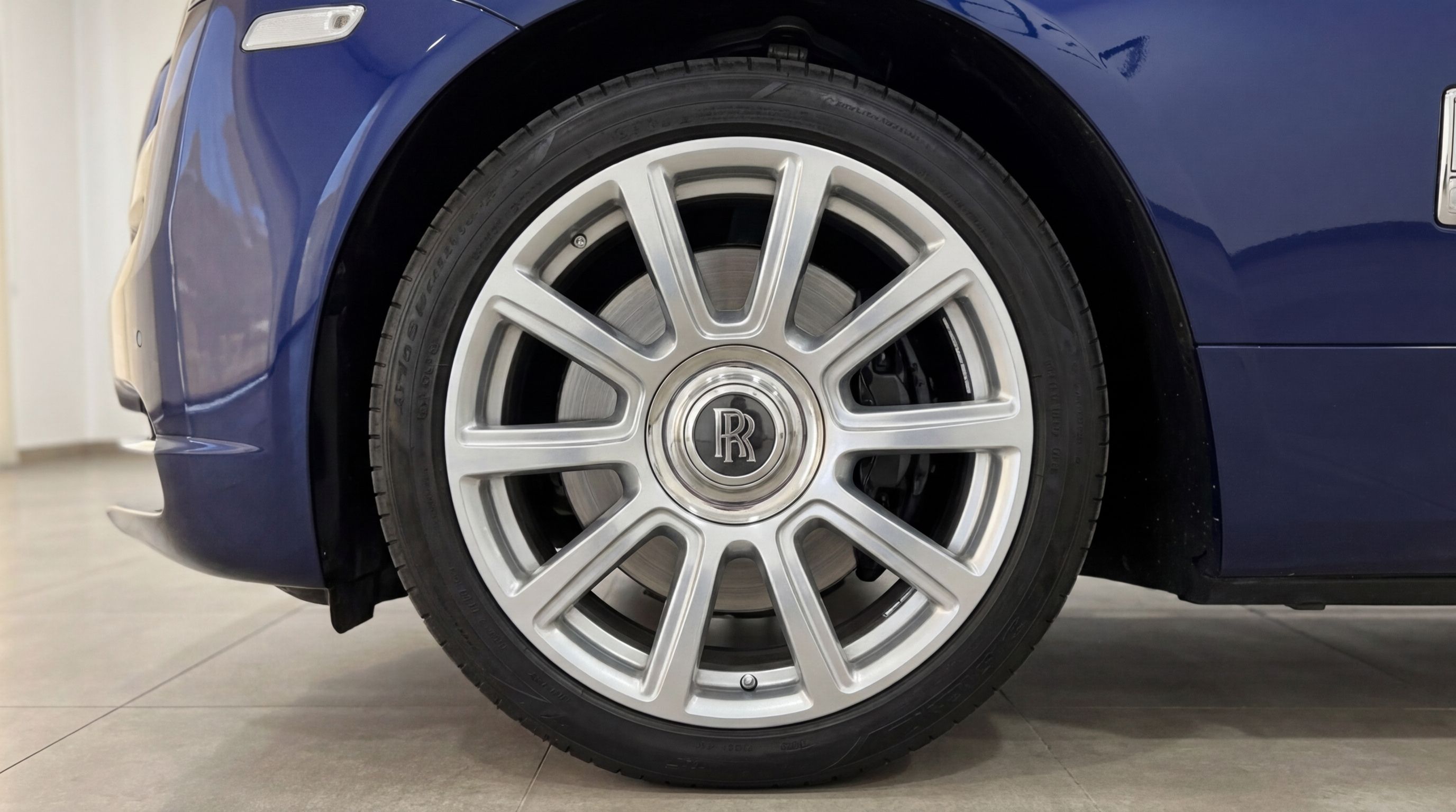 Rolls-Royce Dawn's front wheel with a silver multi-spoke rim and a midnight blue fender, in Barcelona.