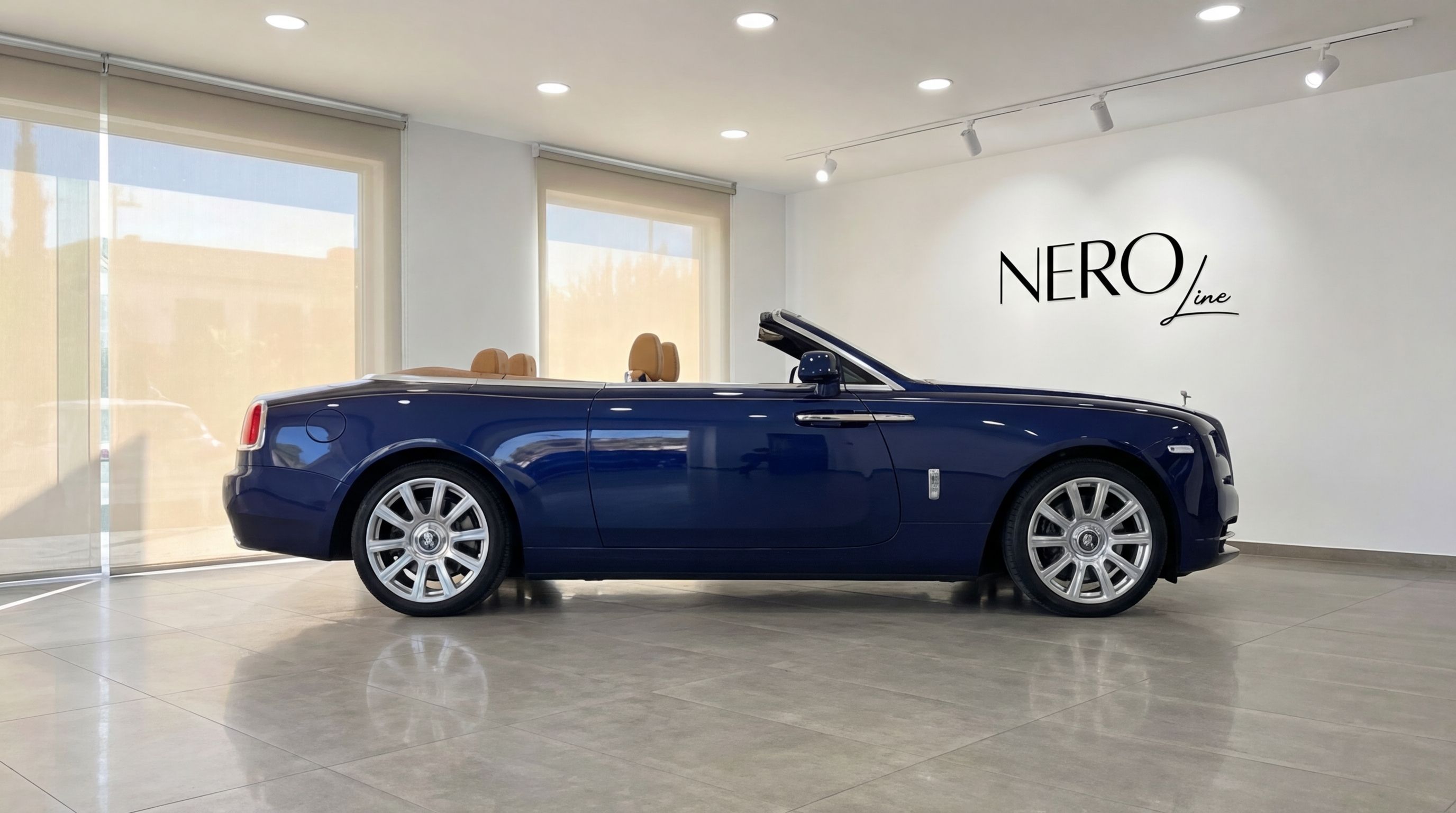 The midnight blue Rolls-Royce Dawn convertible is showcased in a showroom with its top down in Barcelona.