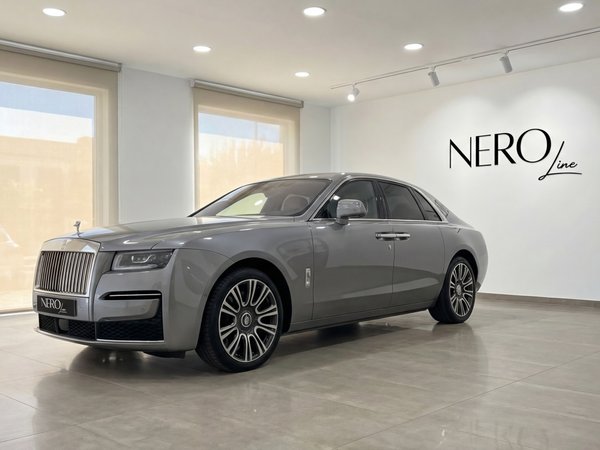 Rolls-Royce Ghost — Vista en showroom en Madrid Un Rolls-Royce Ghost gris metalizado, mostrando su elegante perfil delantero y lateral en un moderno concesionario en Madrid.