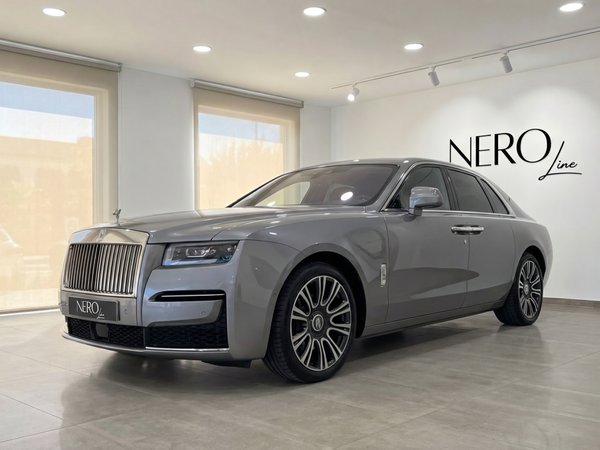 Rolls-Royce Ghost — Luxury sedan in Valencia The metallic gray Rolls-Royce Ghost is elegantly parked in a showroom, showcasing its luxurious front three-quarter view in Valencia.