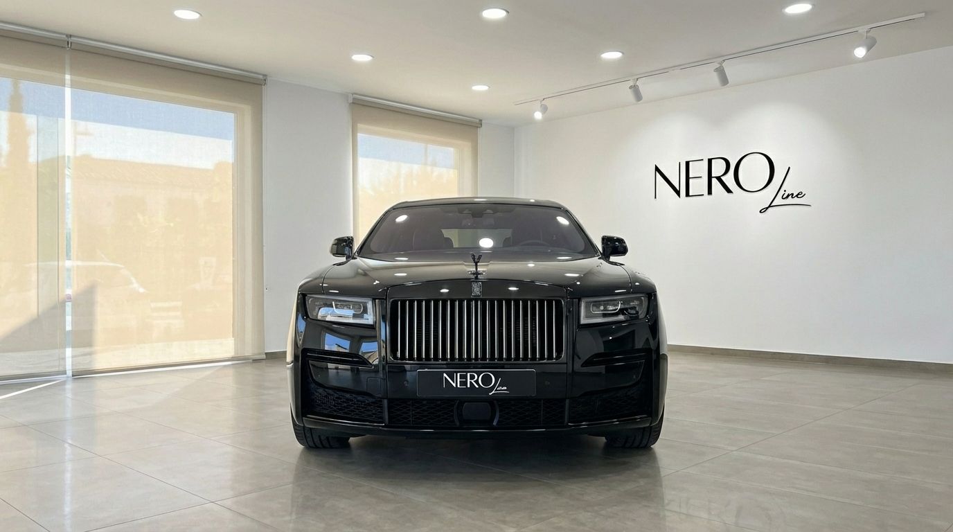 The black 2025 Rolls-Royce Ghost luxury sedan is prominently displayed from a front view in a showroom in Marbella.