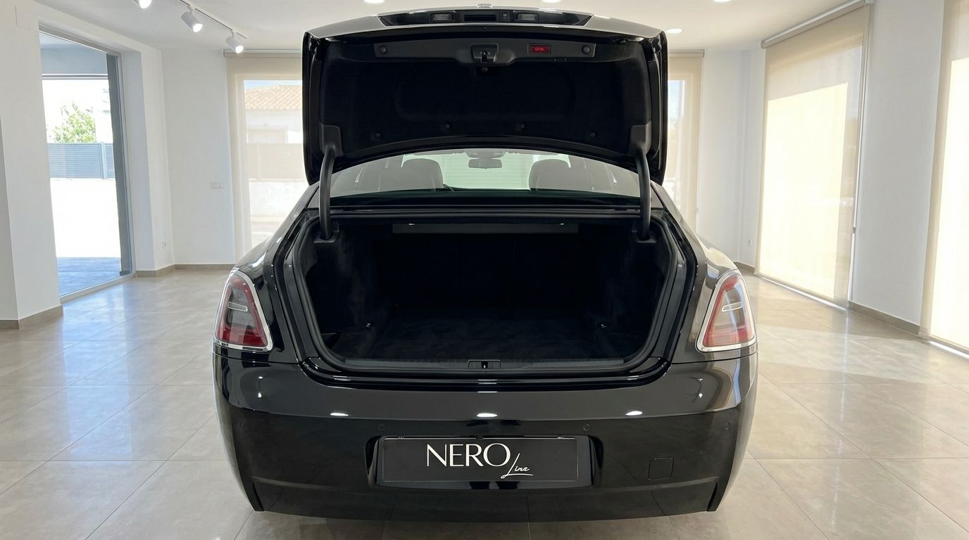 The black 2025 Rolls-Royce Ghost is shown from the rear with its spacious trunk open, parked indoors in Marbella.