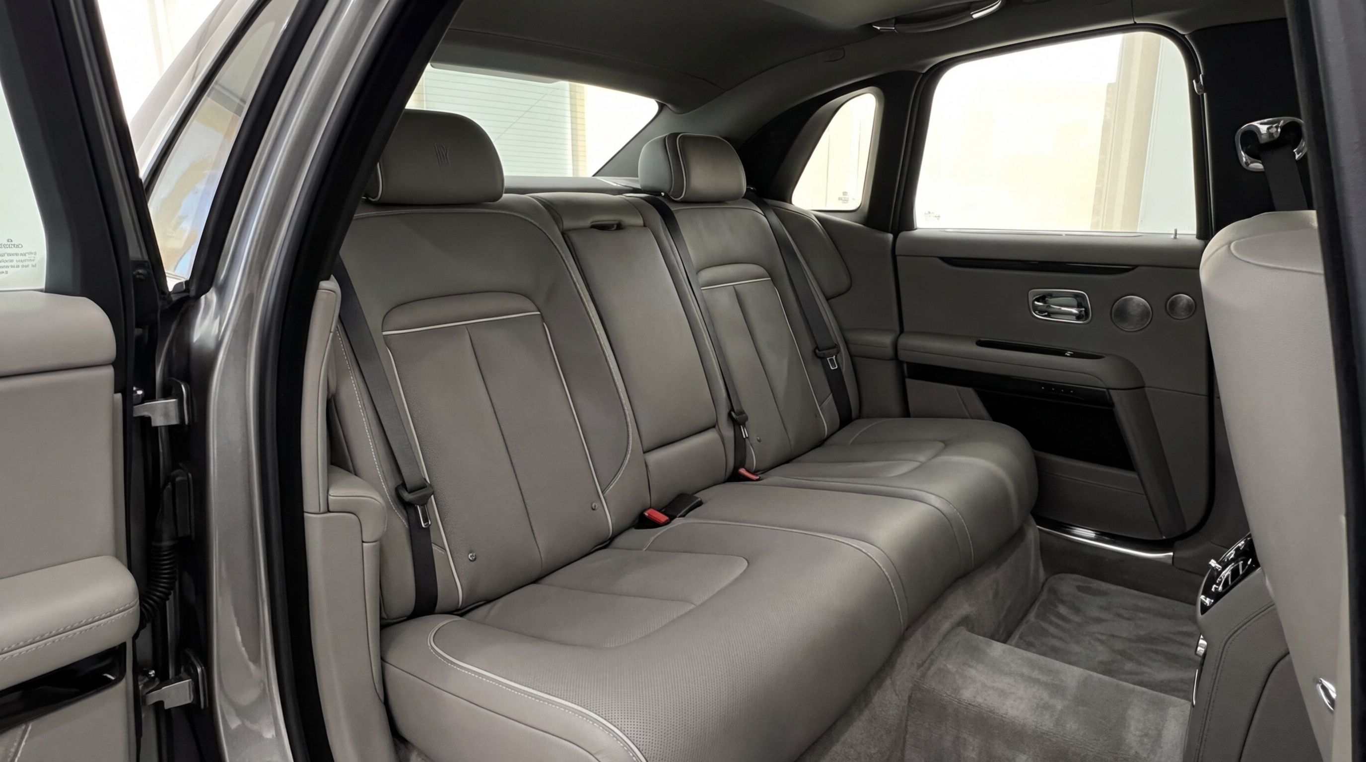 The luxurious rear seats of the metallic gray Rolls-Royce Ghost in Valencia, showcasing premium leather and spacious comfort.