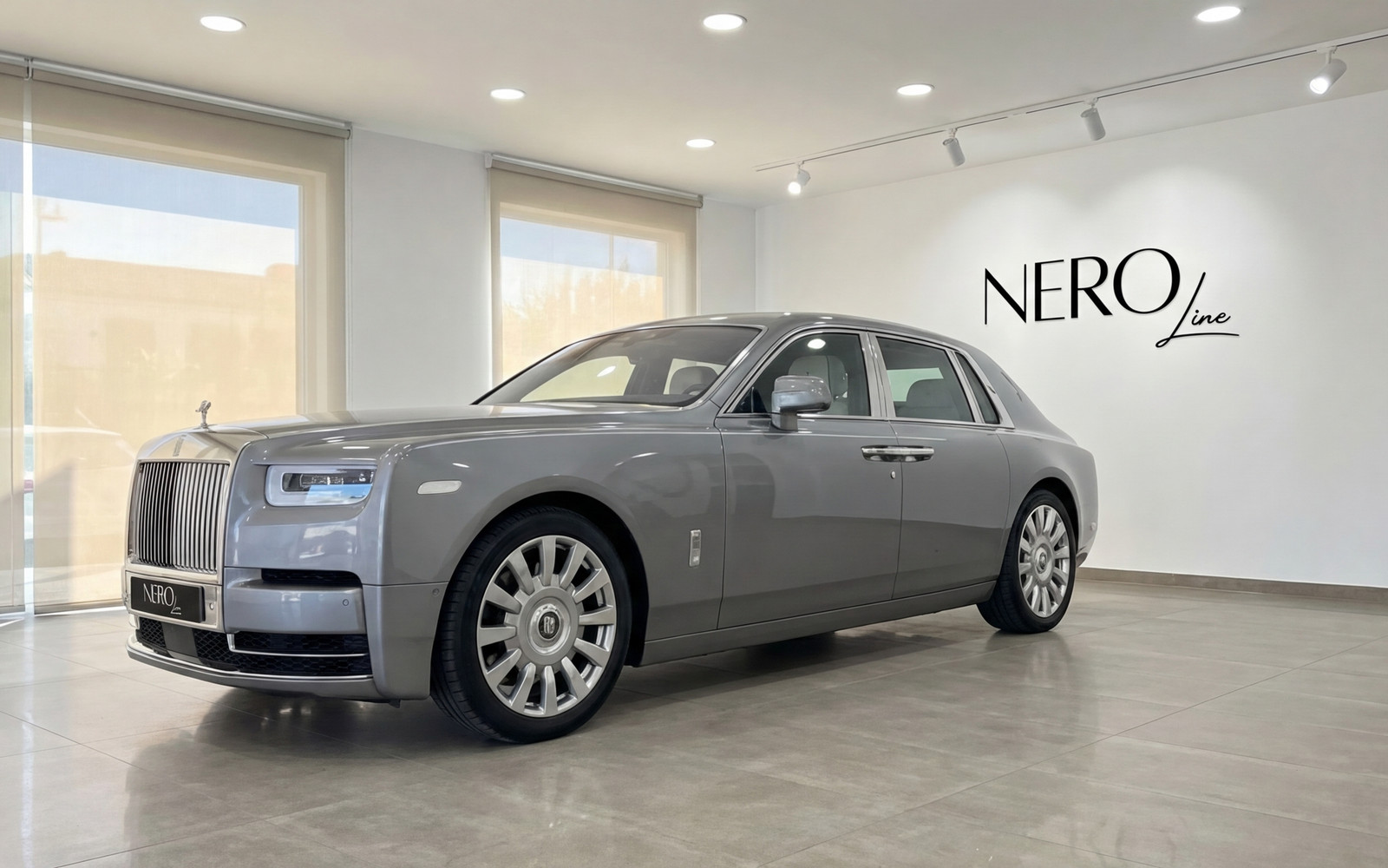 Rolls-Royce Phantom — Luxury Sedan in Mallorca A metallic grey Rolls-Royce Phantom (2024) parked in a showroom in Mallorca, viewed from the front three-quarter angle.