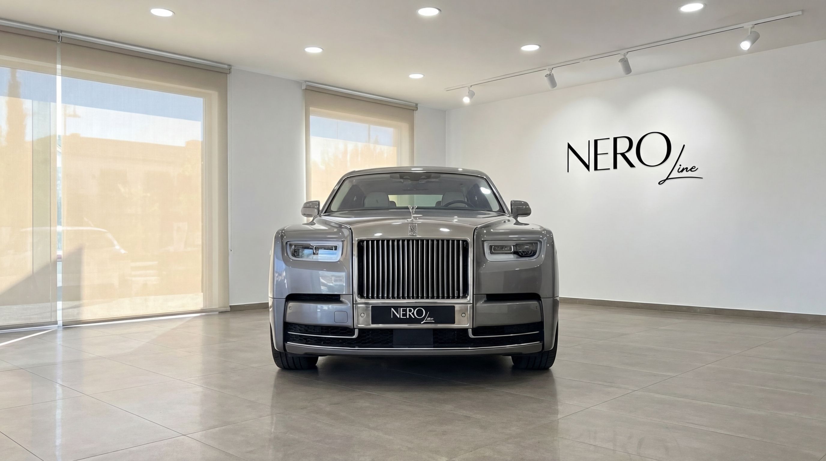The Rolls-Royce Phantom, a metallic grey luxury sedan, is prominently displayed from the front in a bright showroom in Mallorca.