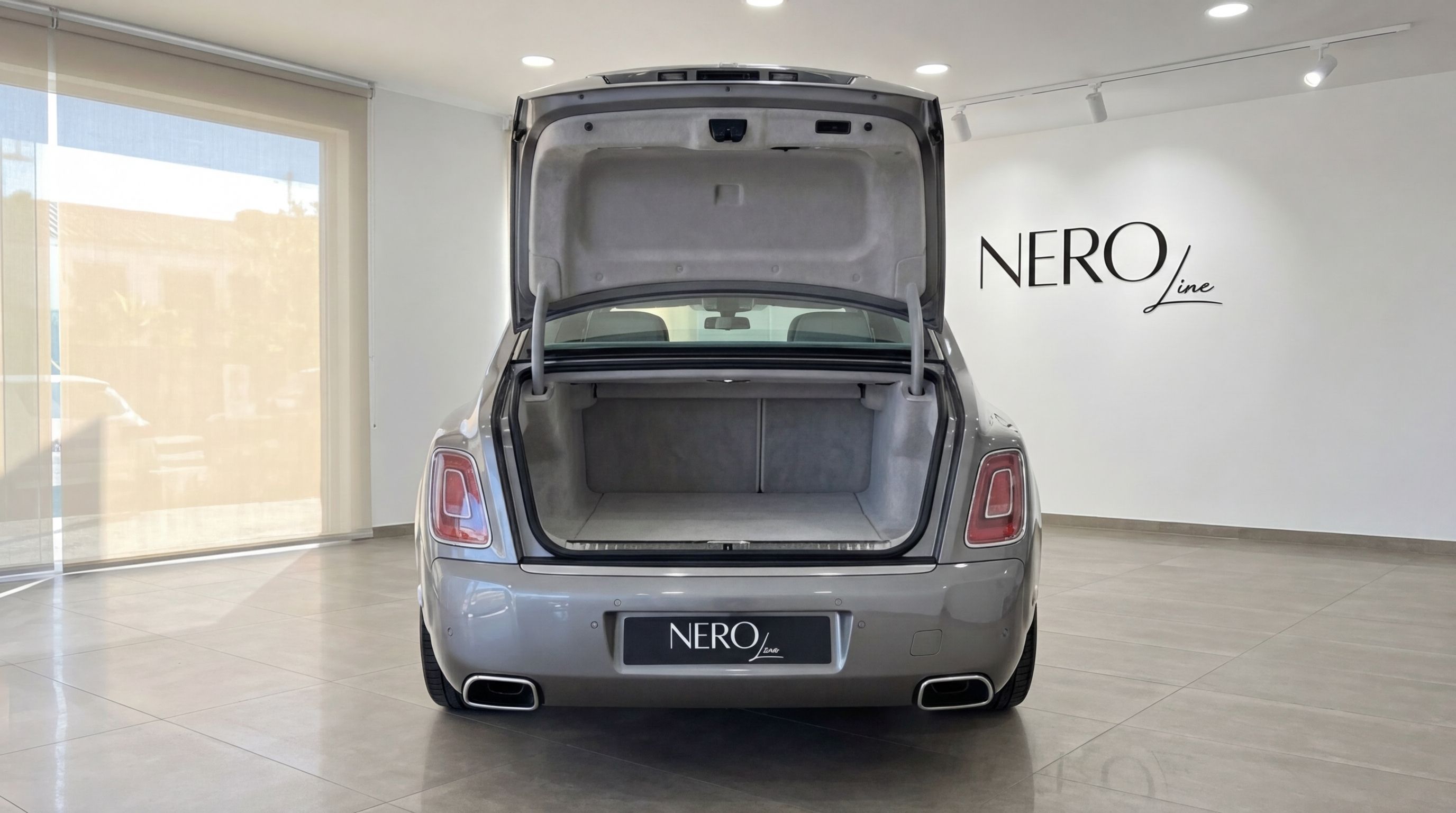 The metallic grey Rolls-Royce Phantom is shown from the rear with its trunk open, in a showroom in Mallorca.