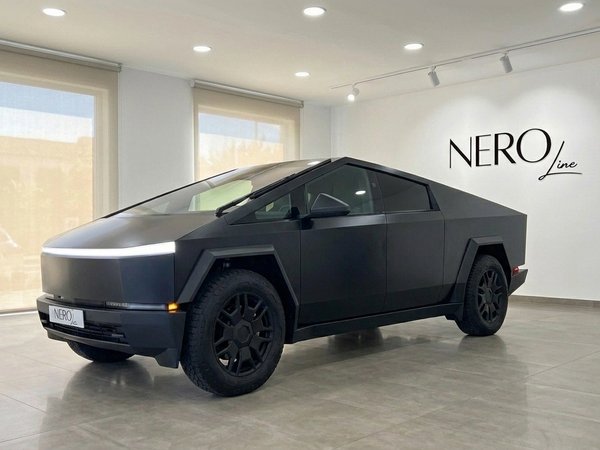 Tesla Cybertruck — Front three-quarter view The matte black Tesla Cybertruck is showcased in a front three-quarter view inside a bright showroom in Marbella.