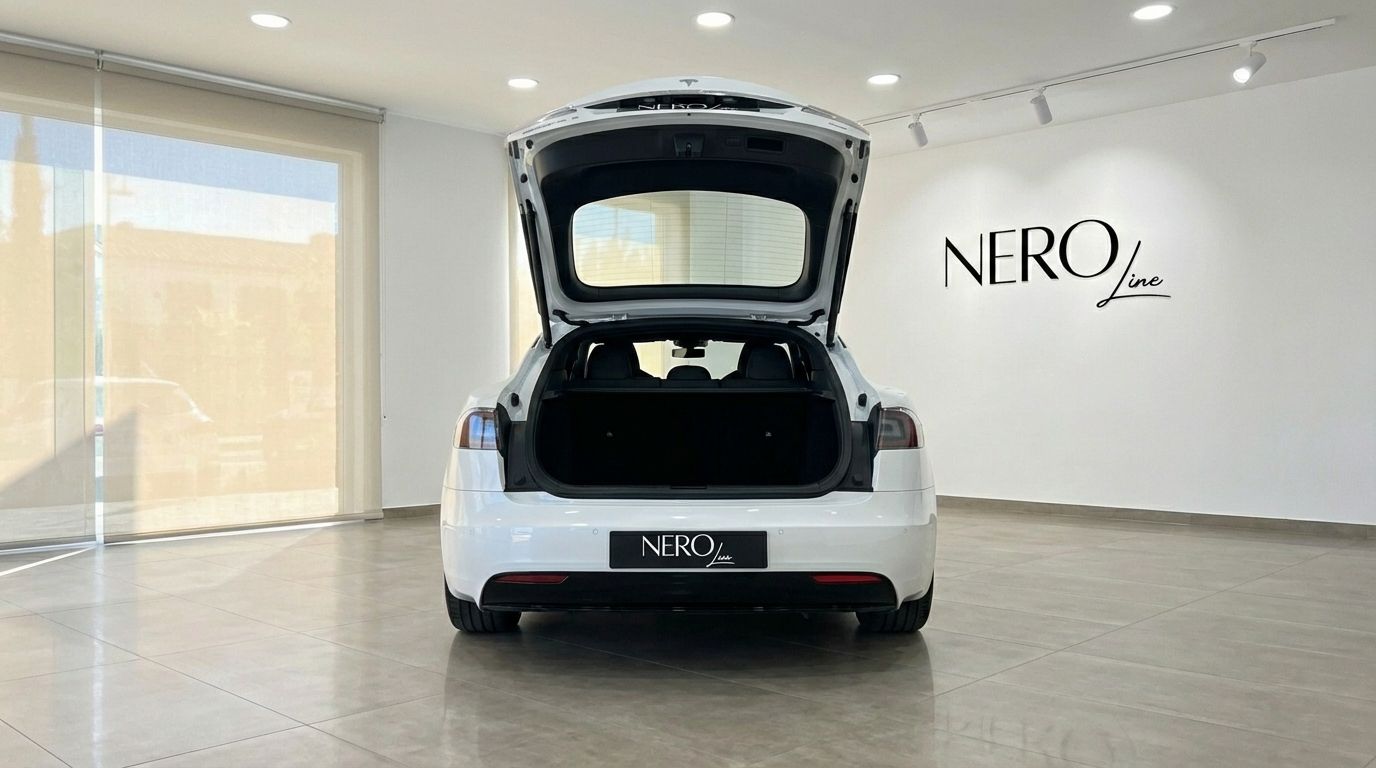 El Tesla Model S Plaid blanco de 2023 se muestra desde la parte trasera con el maletero abierto, revelando un amplio espacio de carga en Alicante.