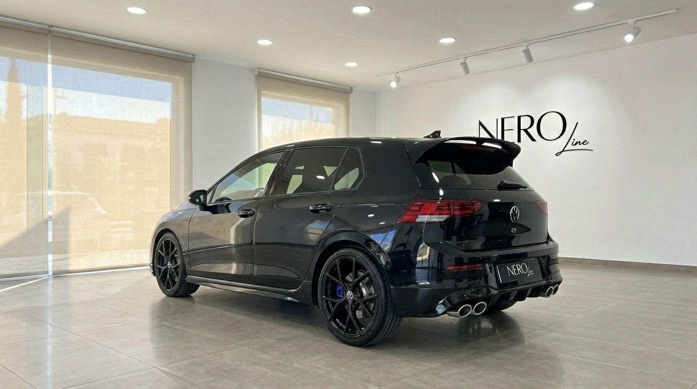 Ein glänzend schwarzer Volkswagen Golf R 2.0 TSI 4Motion DSG in einer Dreiviertel-Heckansicht, geparkt in einem modernen Showroom in Alicante.