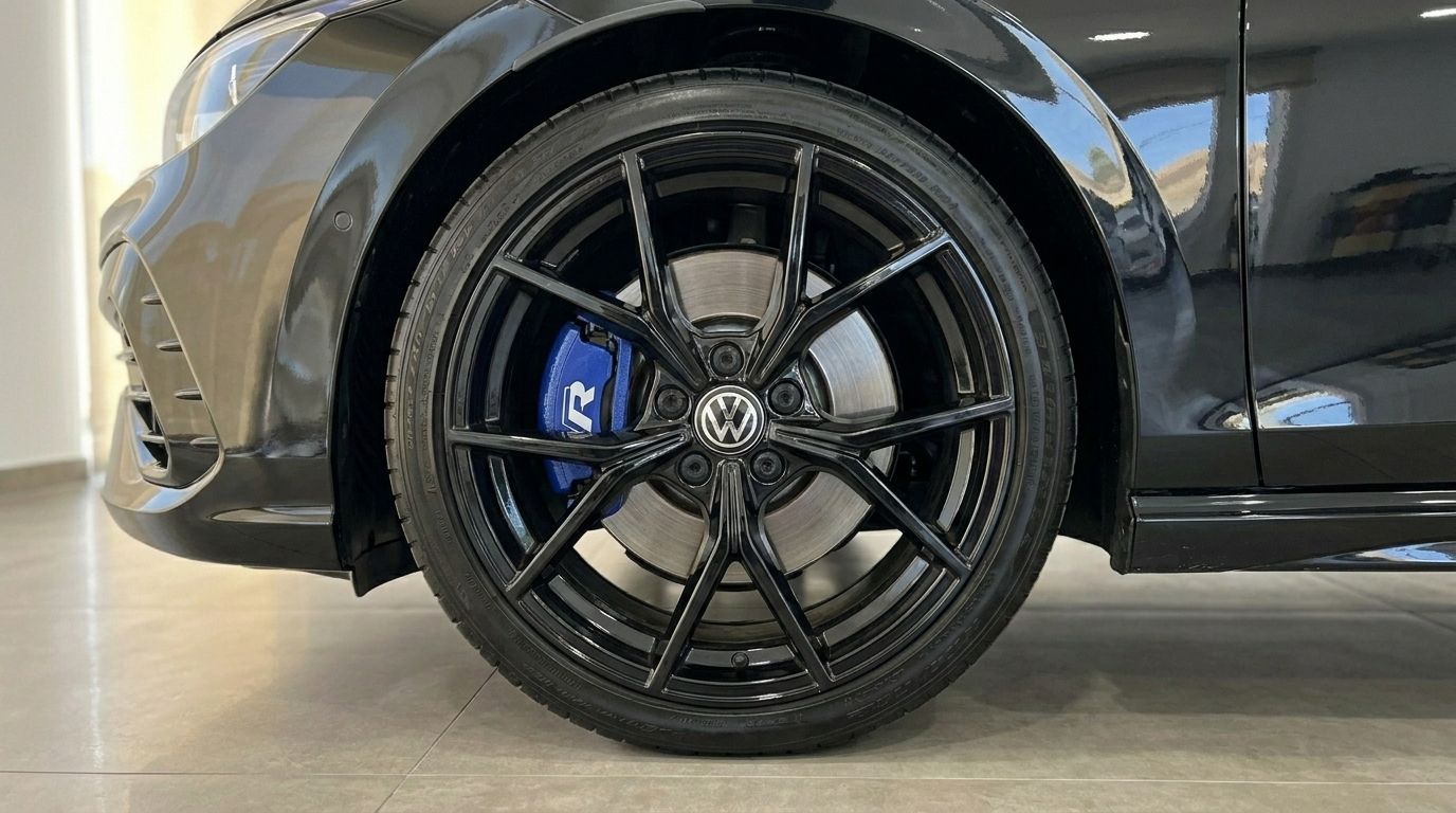 Das Vorderrad des Volkswagen Golf R 2.0 TSI 4Motion DSG, mit schwarzer Mehrspeichenfelge und markantem blauem Bremssattel, sichtbar in Alicante.