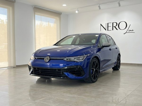 Volkswagen Golf R — Luxury car rental Marbella The metallic blue 2023 Volkswagen Golf R is prominently displayed in a modern showroom in Marbella.