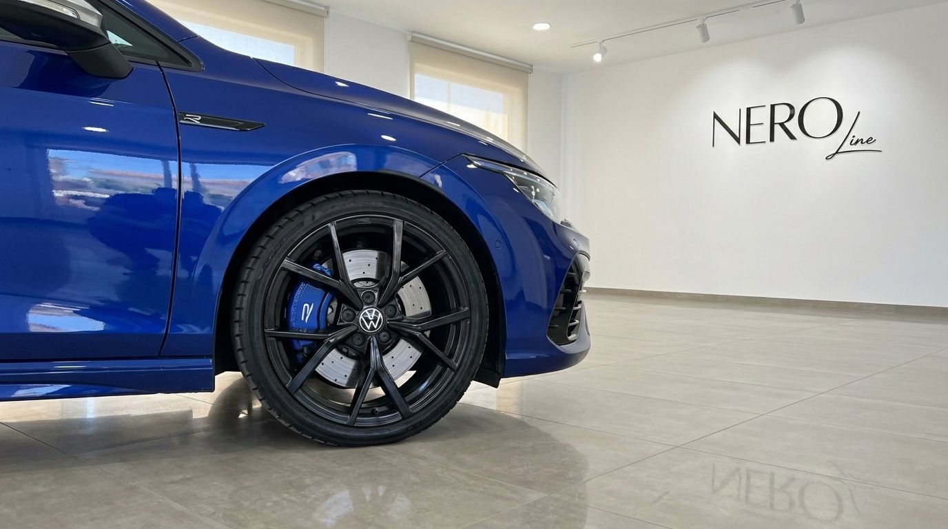 The metallic blue Volkswagen Golf R's front wheel and blue brake caliper are prominently displayed in a Marbella showroom.