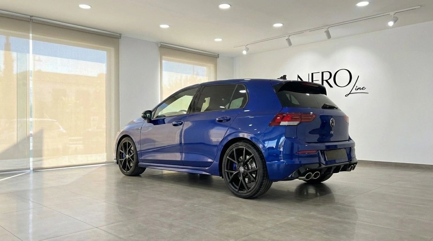 The metallic blue 2023 Volkswagen Golf R is showcased from a rear three-quarter view in a showroom in Marbella.