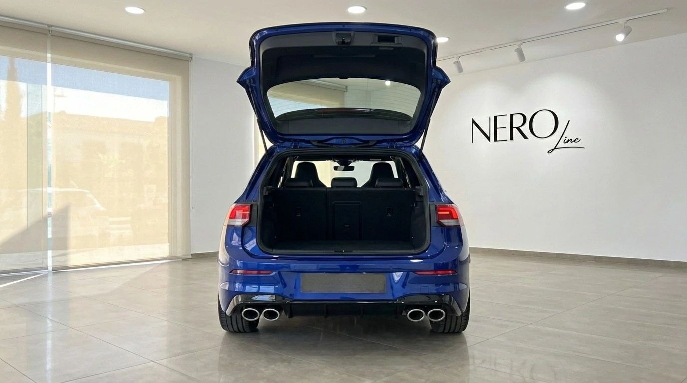 The rear view of the metallic blue 2023 Volkswagen Golf R in Marbella, showcasing its open trunk and quad exhaust pipes.