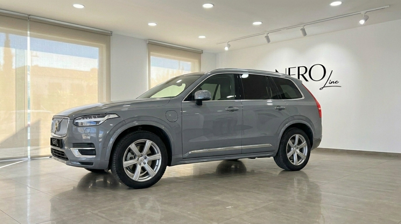 Volvo XC90 — Location de SUV Premium à Marbella Le SUV de luxe Volvo XC90 2023 gris brillant est présenté de trois quarts avant dans un showroom moderne à Marbella.
