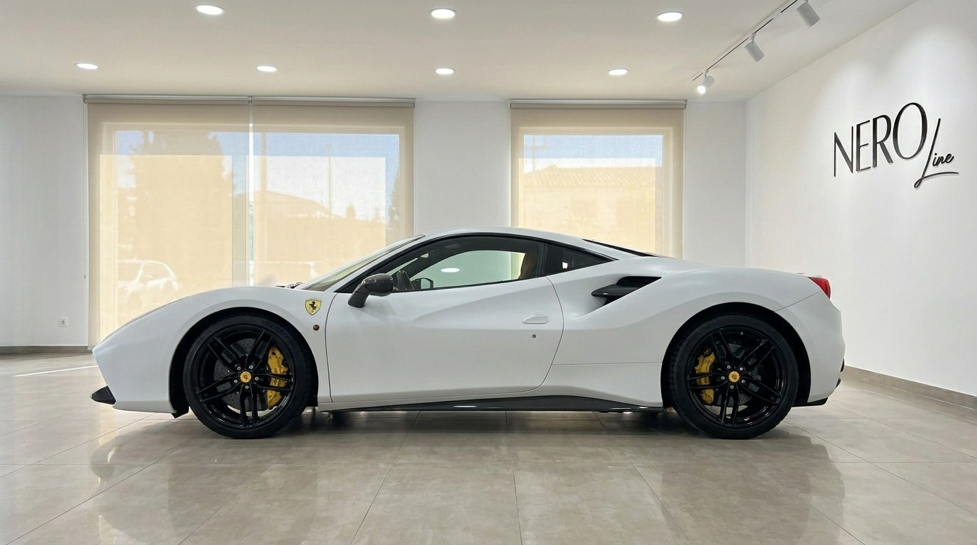 El Ferrari 488 GTB blanco mate se exhibe elegantemente de perfil en un moderno showroom en Madrid.