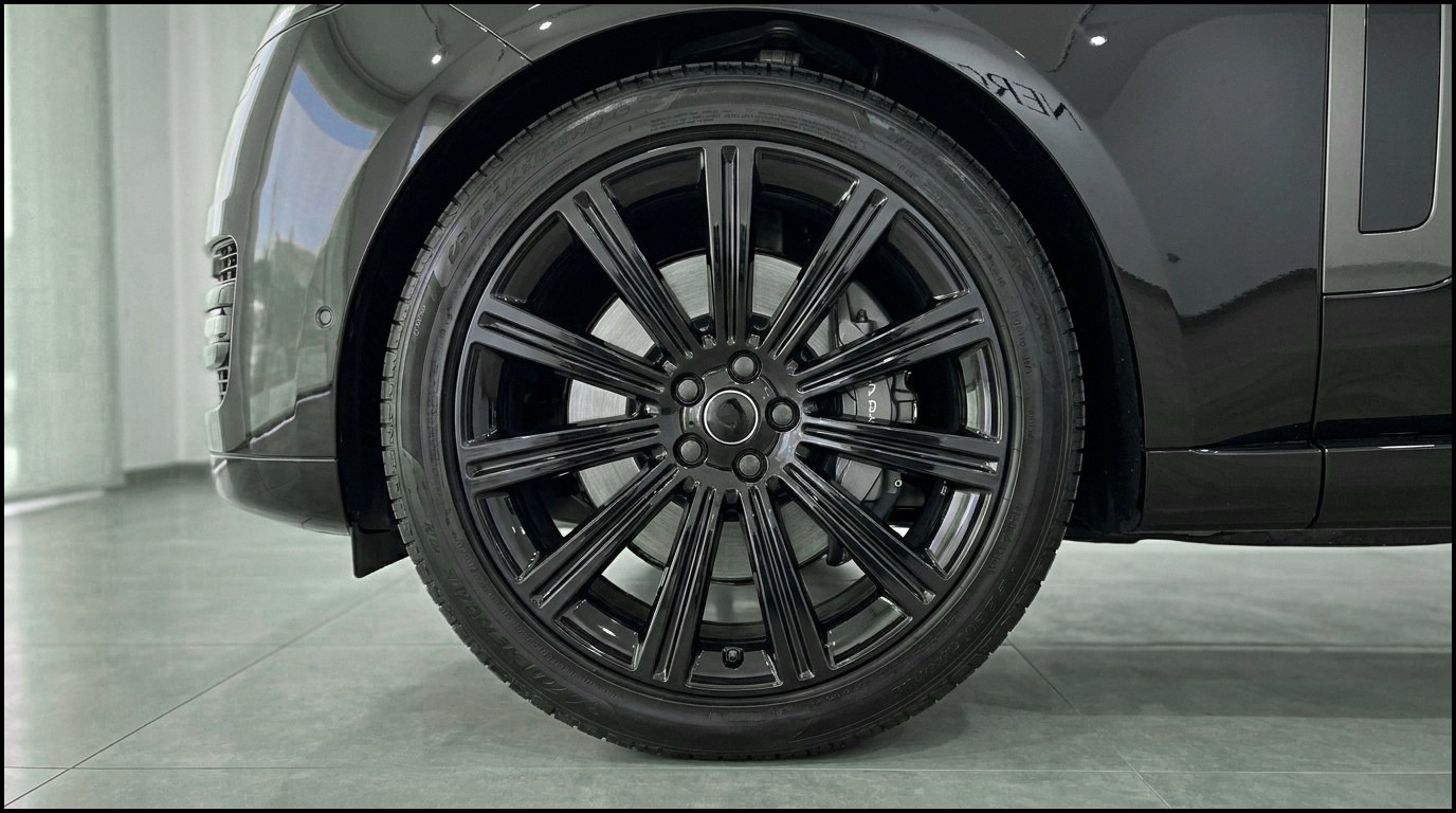 Black Range Rover Vogue LWB front wheel with gloss black multi-spoke rim and brake caliper, parked in Marbella.