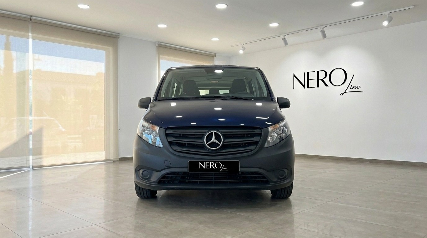 The dark blue Mercedes-Benz Vito Tourer 119 CDI is parked head-on in a bright showroom in Alicante, showcasing its front grille.