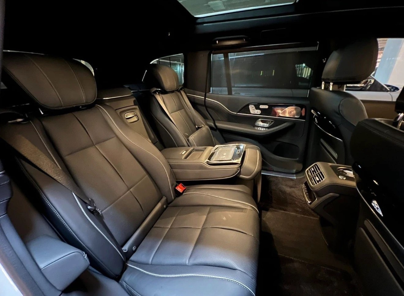 The luxurious rear interior of the Mercedes-Benz GLS680 MAYBACH in Madrid, featuring black leather seats, a center console, and a tablet.