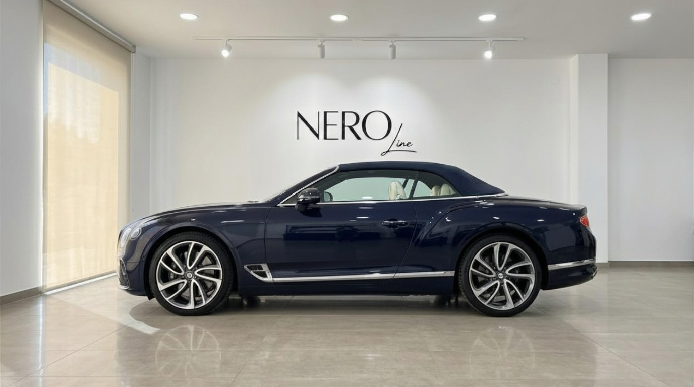 The Bentley Continental GTC convertible in Gloss Dark Sapphire Blue is showcased in a side profile view inside a showroom in Barcelona.